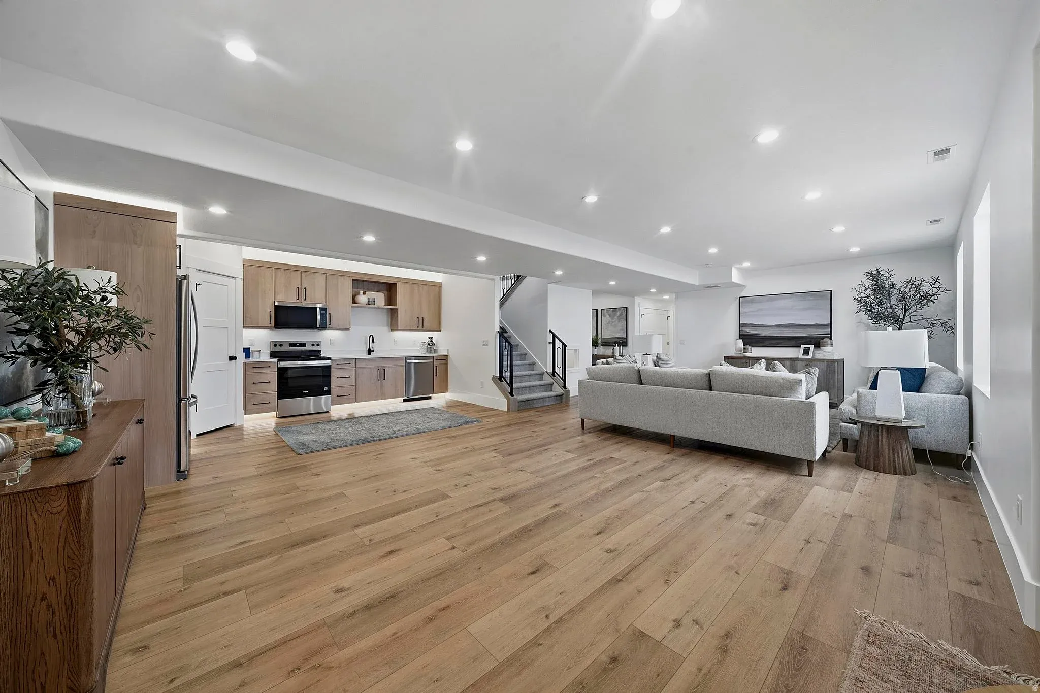 An Eagle Point Homes living area with a neutral sofa, bright kitchen, and wood flooring
